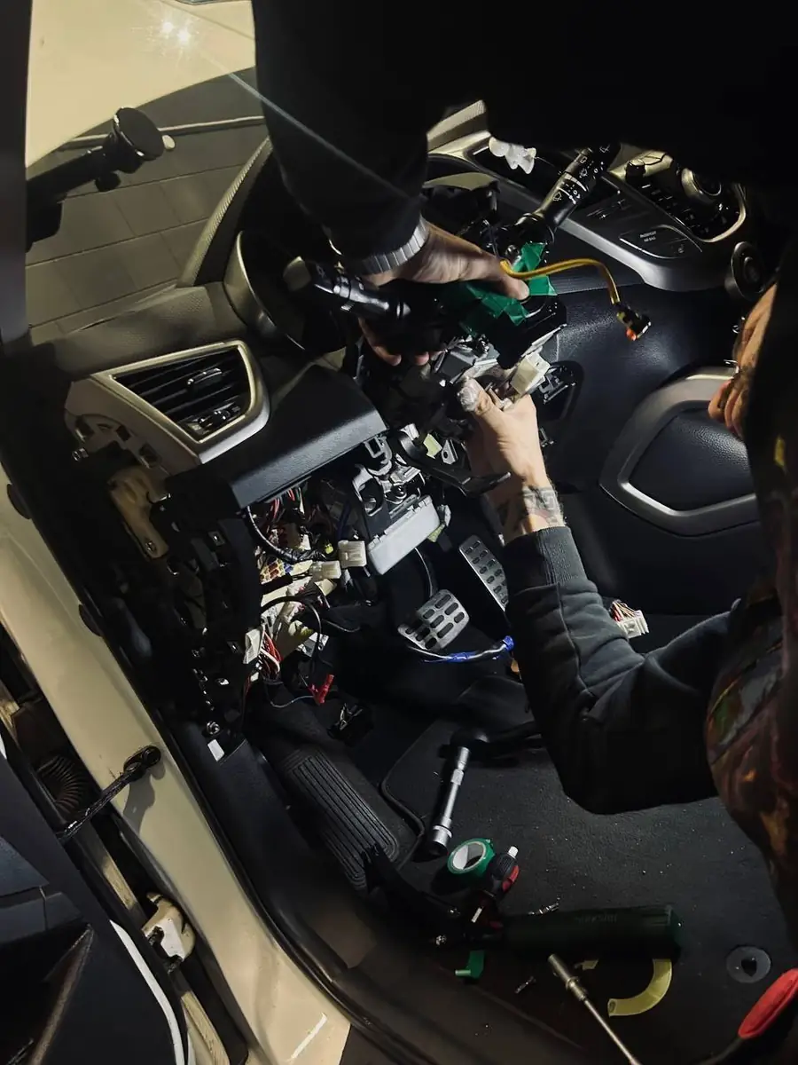 Elektronica-monteur van AutoJet werkt aan de bedrading van een auto in de werkplaats in Almere